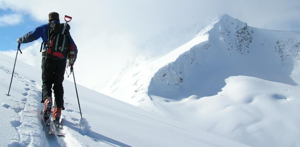 man hiking up on skis to the top of a mountain